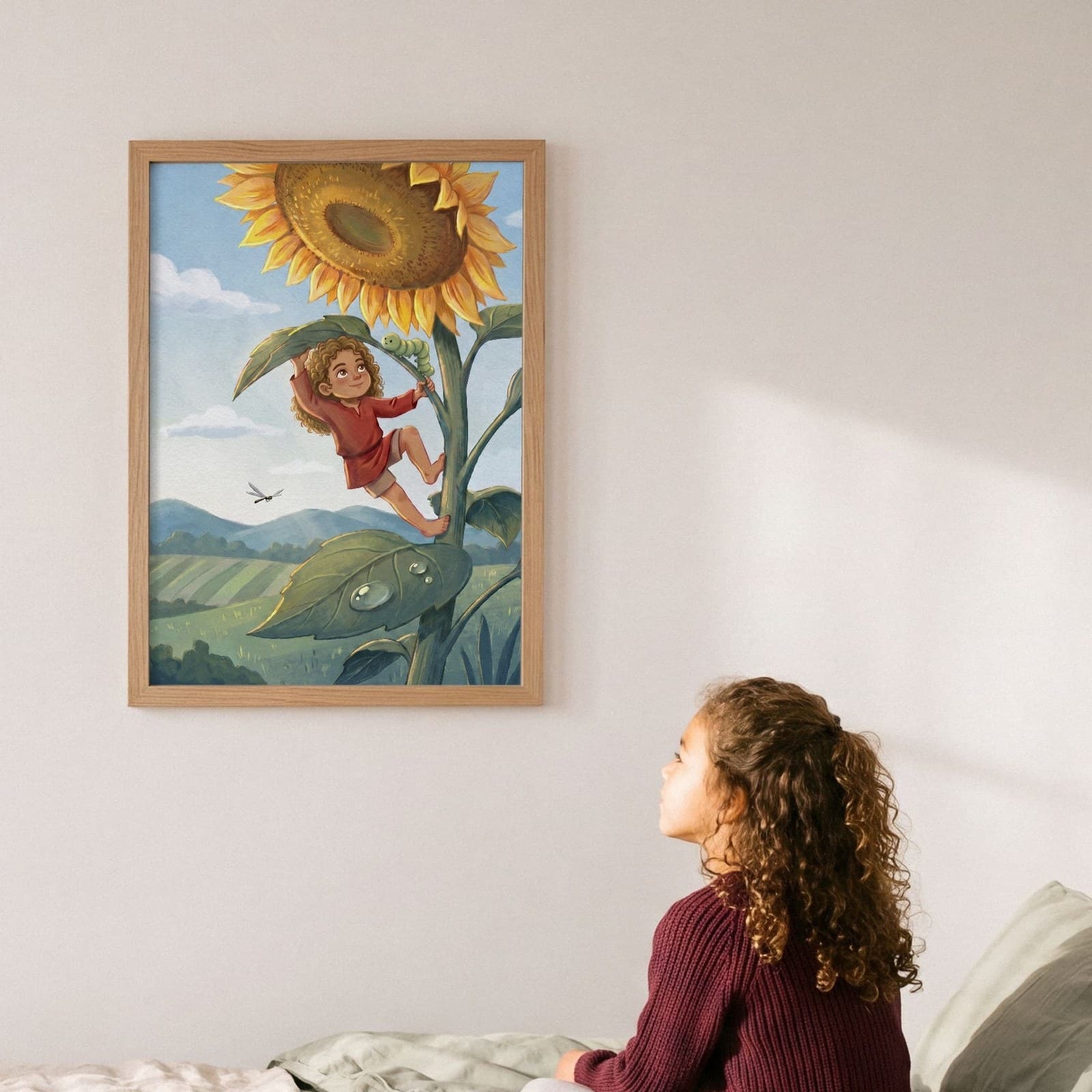 A framed print of a child climbing a giant sunflower, hanging above a bed where a girl sits looking up at it